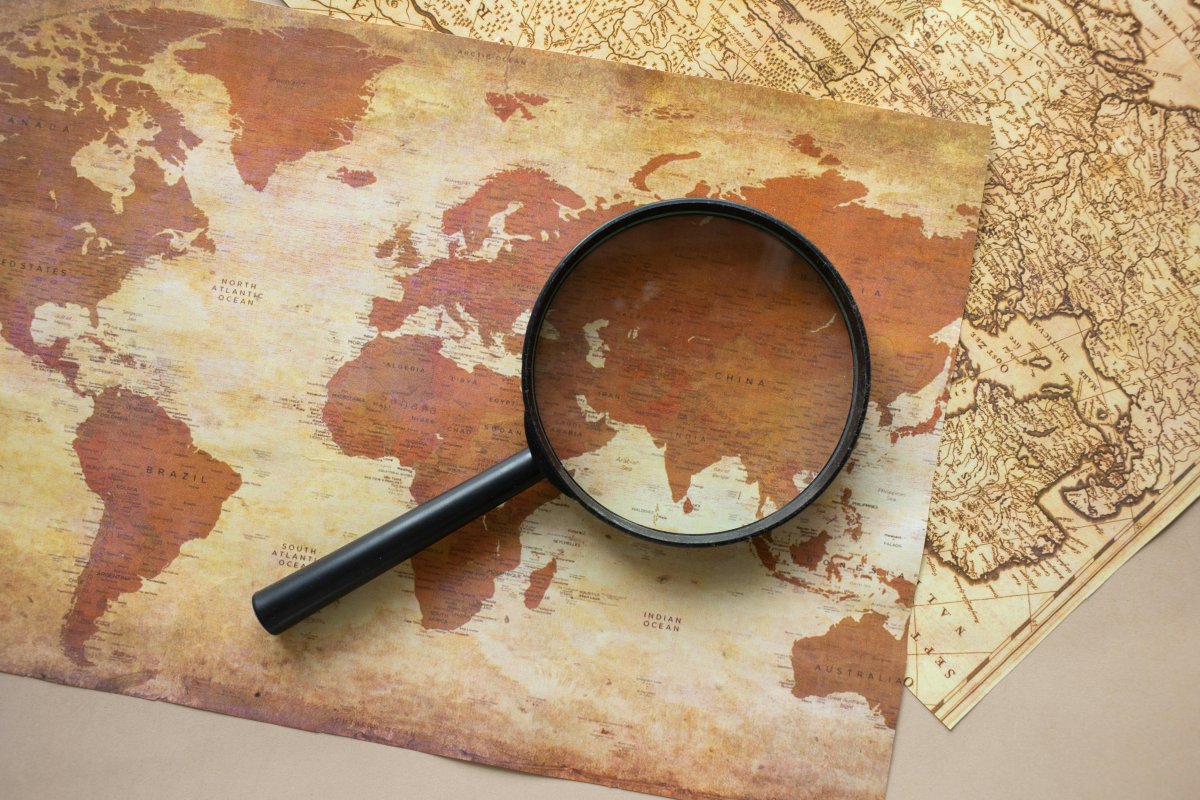 A few maps with a black magnifying glass on top of them