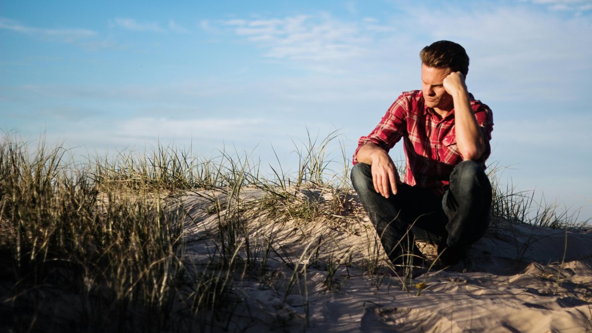A man sitting on the beach deep in thought